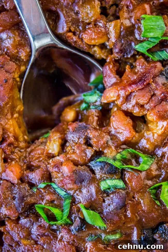 Smoky Baked Beans with Bacon Recipe 3 a serving spoon in a pan of bacon baked beans.