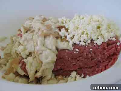 Adding bread and feta to meat for greek recipe keftedes kalokairinoi summer meatballs.
