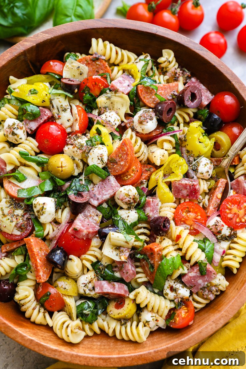 A large wooden serving bowl filled with Italian antipasto pasta salad