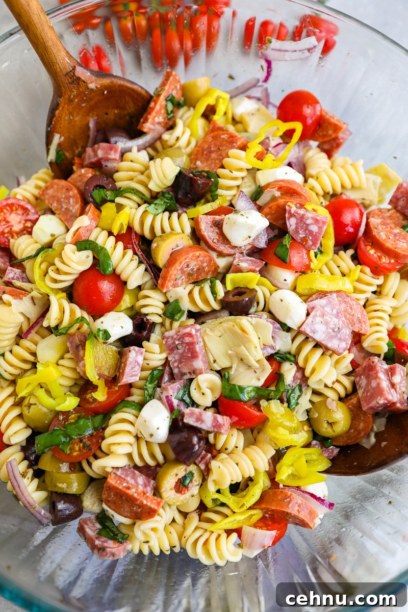 A large clear mixing bowl filled with freshly made Italian antipasto pasta salad