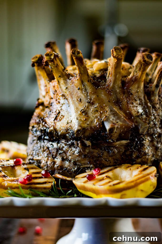 9 Elegant Christmas Dinner Main Course Recipes 4 A cooked crown roast of pork sits on a white serving tray with grilled pears and fresh rosemary around the roast.
