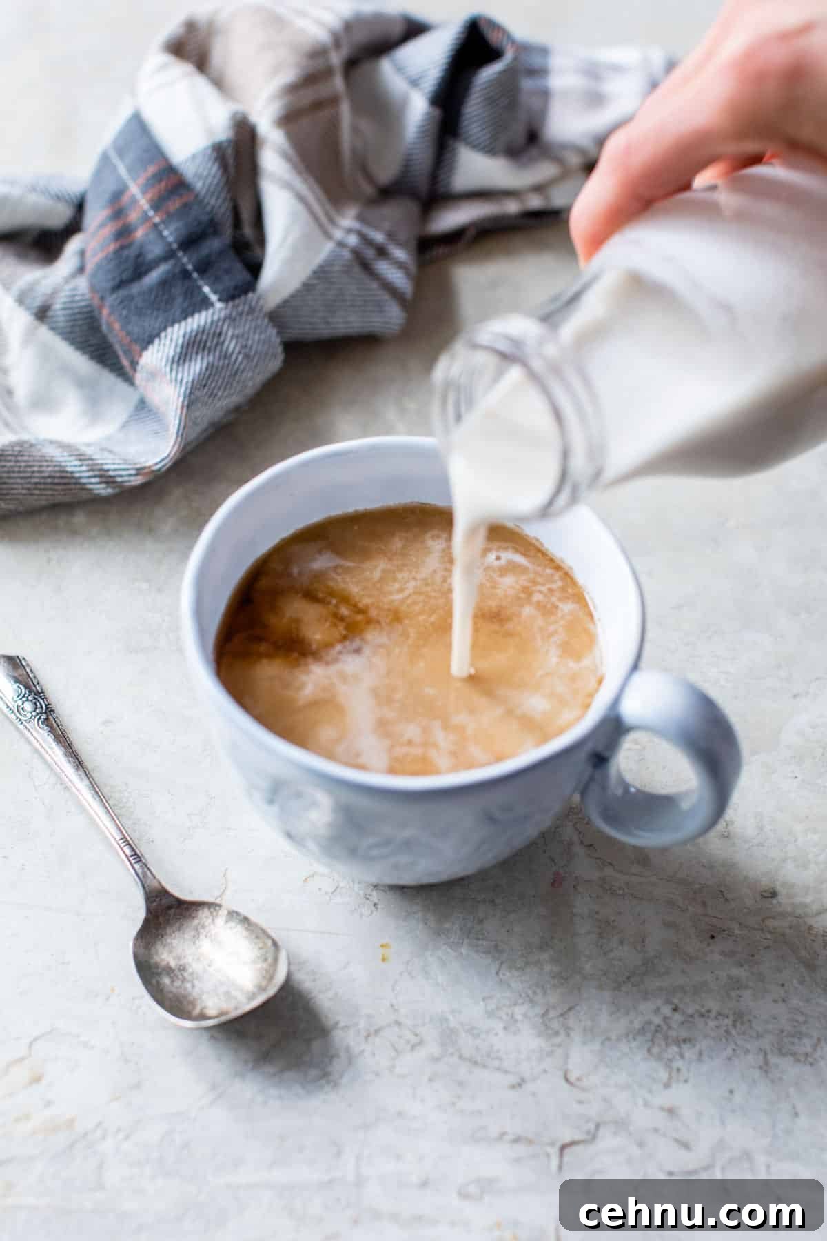 someone pouring coffee creamer into a mug of coffee