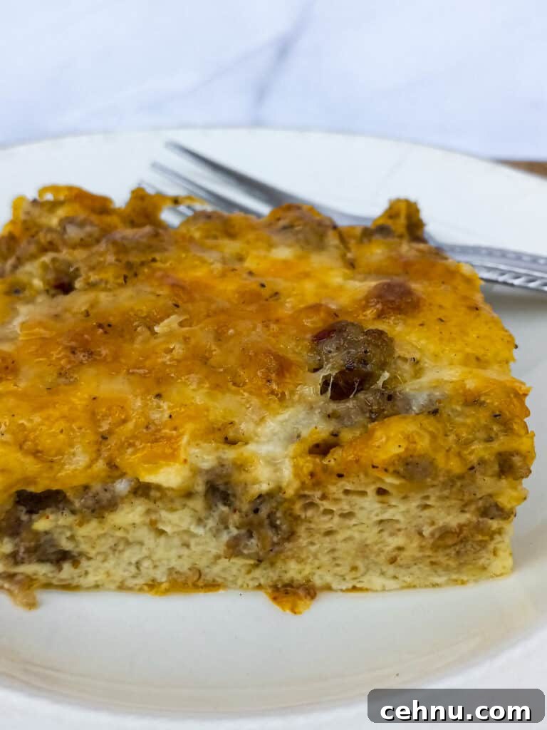 one slice of meat, cheese, and egg breakfast casserole, and a fork on a plate