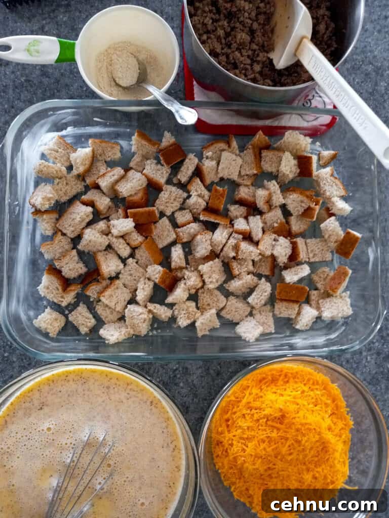 bread cubes in pan, beaten eggs and milk in a bowl, cooked sausage in a pot, cheese in a bowl, and flour mixture in a cup