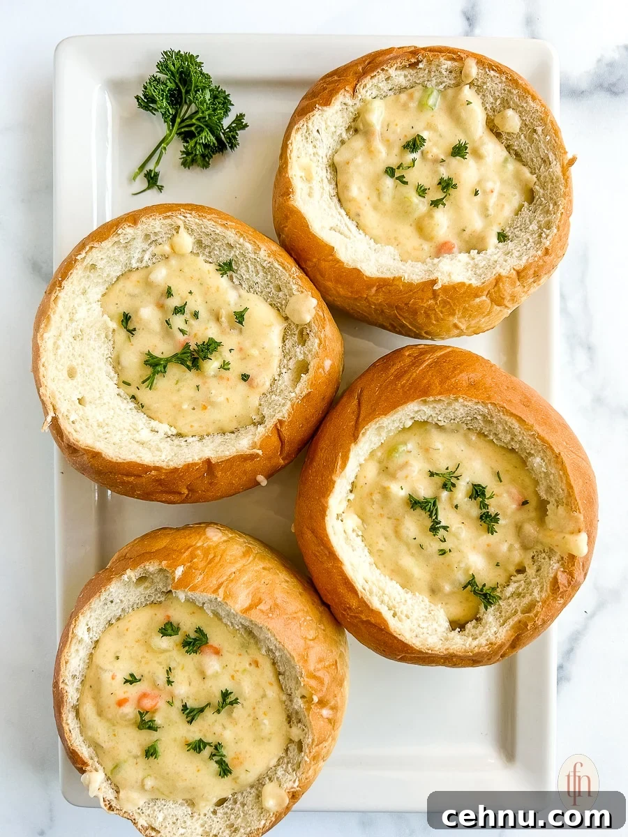 15+ Homemade Soup Recipes for Cozy Weeknight Meals 23 Four bread bowls filled with creamy soup garnished with fresh herbs.