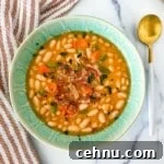 15+ Homemade Soup Recipes for Cozy Weeknight Meals 10 A green bowl with great northern bean soup with a golden spoon and a striped red kitchen towel.