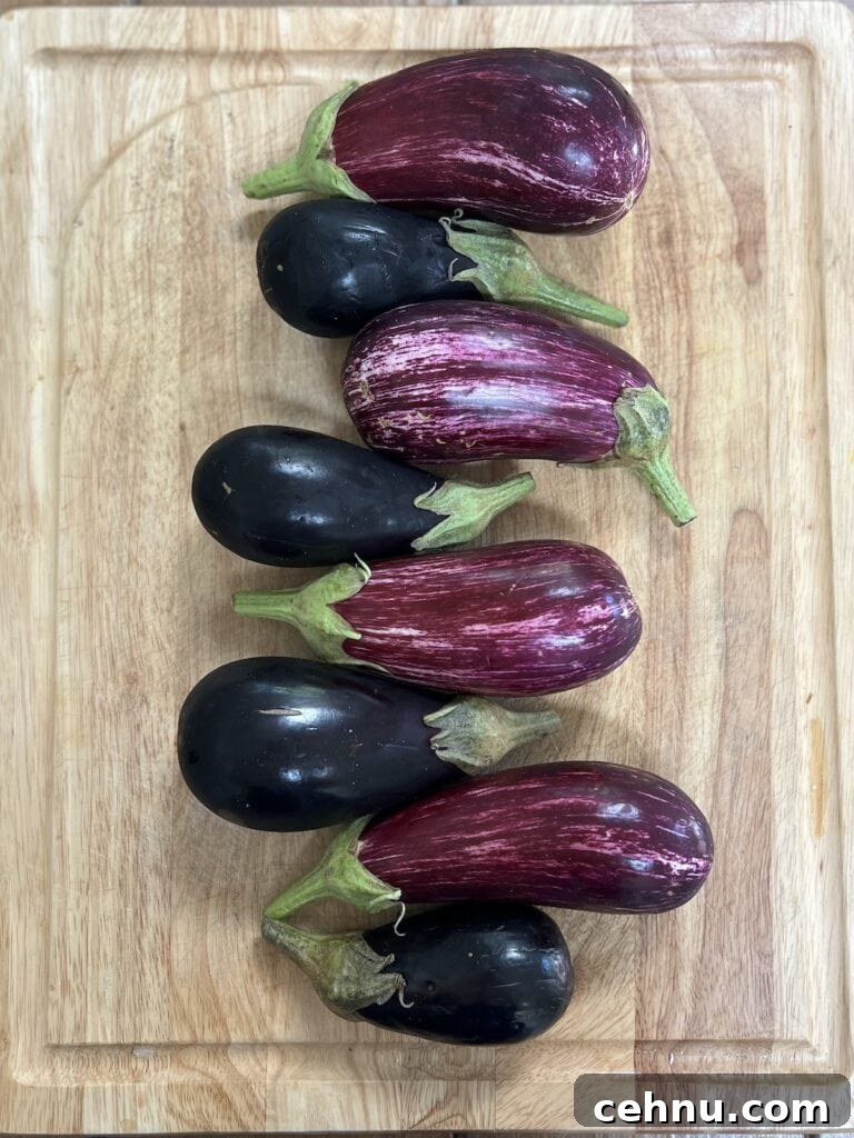 Four black Italian eggplant and four light purple Luicilla eggplant on a cutting board.