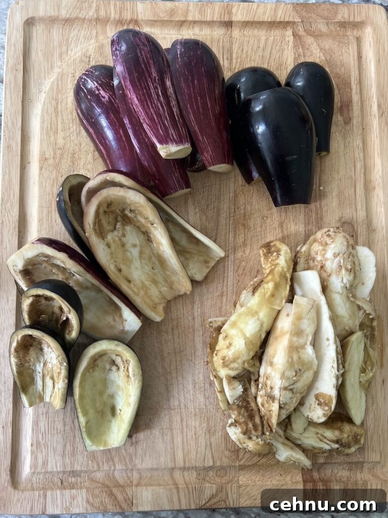 Overhead view of hollowed out eggplant with eggplant pulp next to them on cutting board.