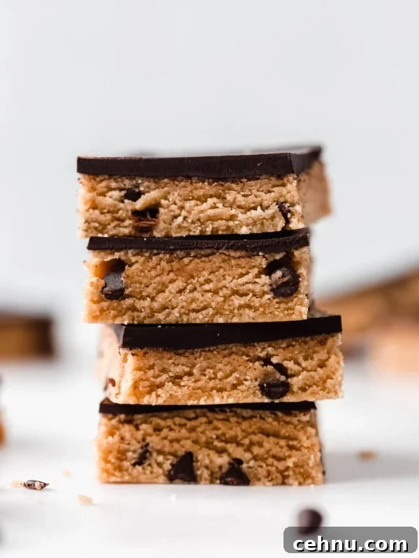 a stack of cookie dough bars topped with dark chocolate