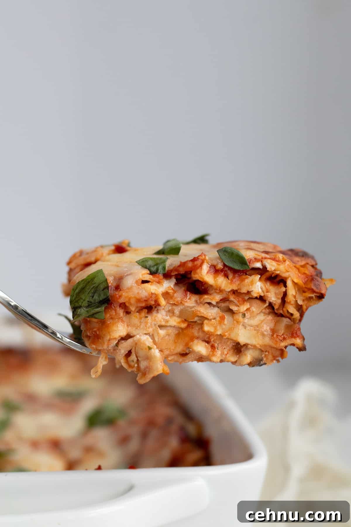 5-Ingredient Matzo Lasagna for Passover Dinner 2 a piece of matzo lasagna on a serving fork over the baking dish
