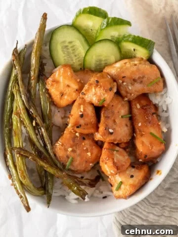 salmon bites in a rice bowl with cucumber and green beans.