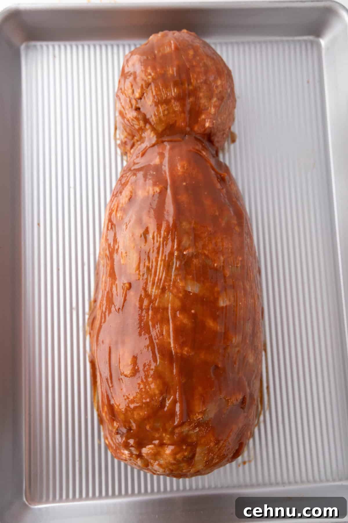 Halloween Mummy Meatloaf Recipe 11 Uncooked mummy meatloaf coated with sauce.
