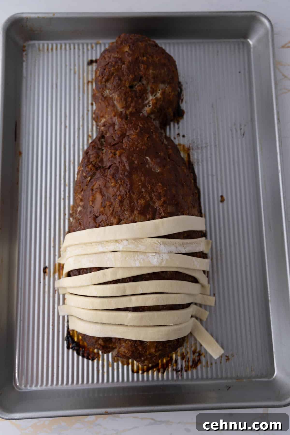 Halloween Mummy Meatloaf Recipe 12 Mummy meatloaf partly wrapped in dough strips.