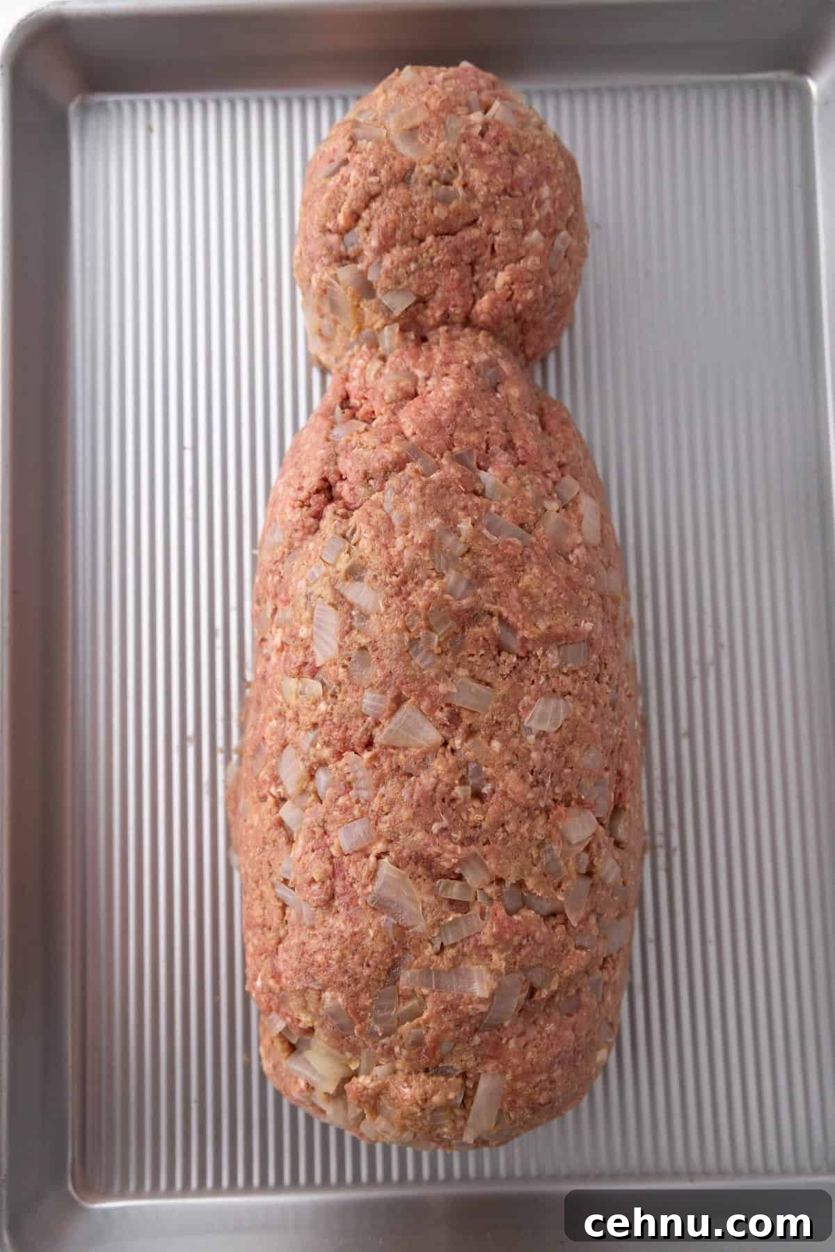 Halloween Mummy Meatloaf Recipe 10 Ground meat shaped into a mummy body on a baking tray.