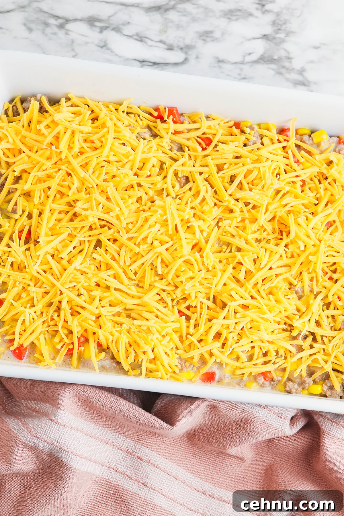 Cheesy Tater Tot Casserole with Ground Beef Recipe 8 Cheese added to casserole filling in baking dish.