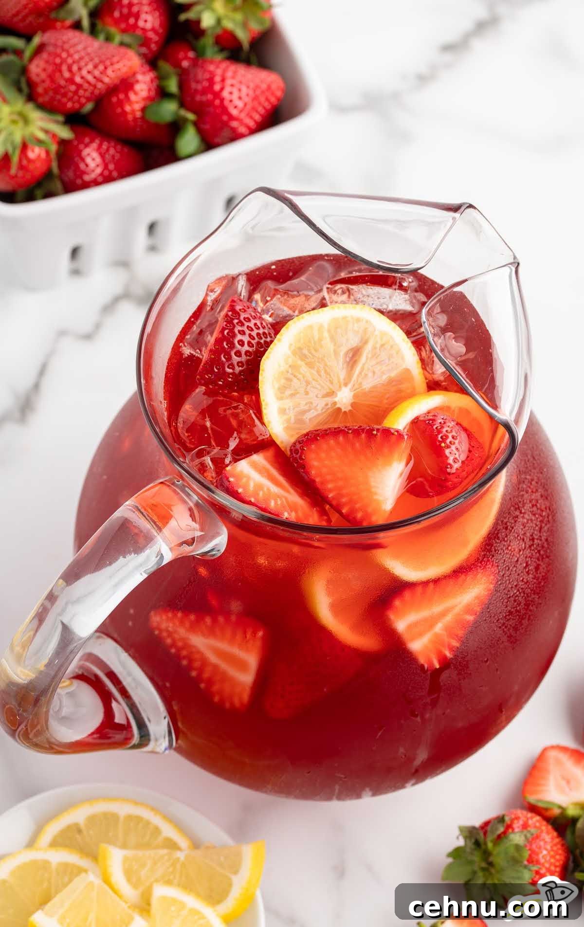Overhead view of a glass pitcher filled with strawberry sweet tea, lemon slices, and strawberries.
