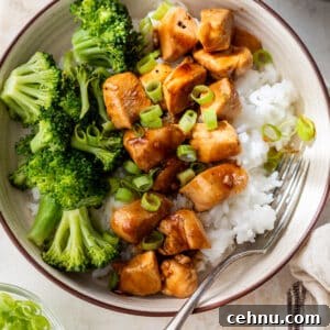 teriyaki chicken and broccoli served over white rice in a bowl.