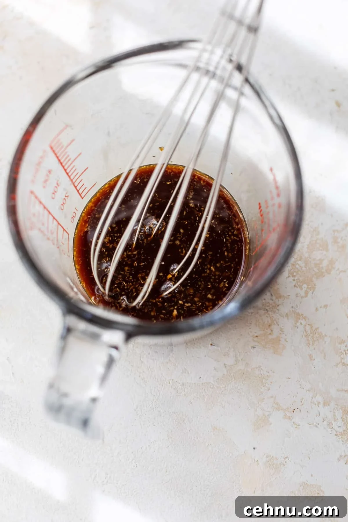 whisking homemade teriyaki sauce in a glass measuring cup.