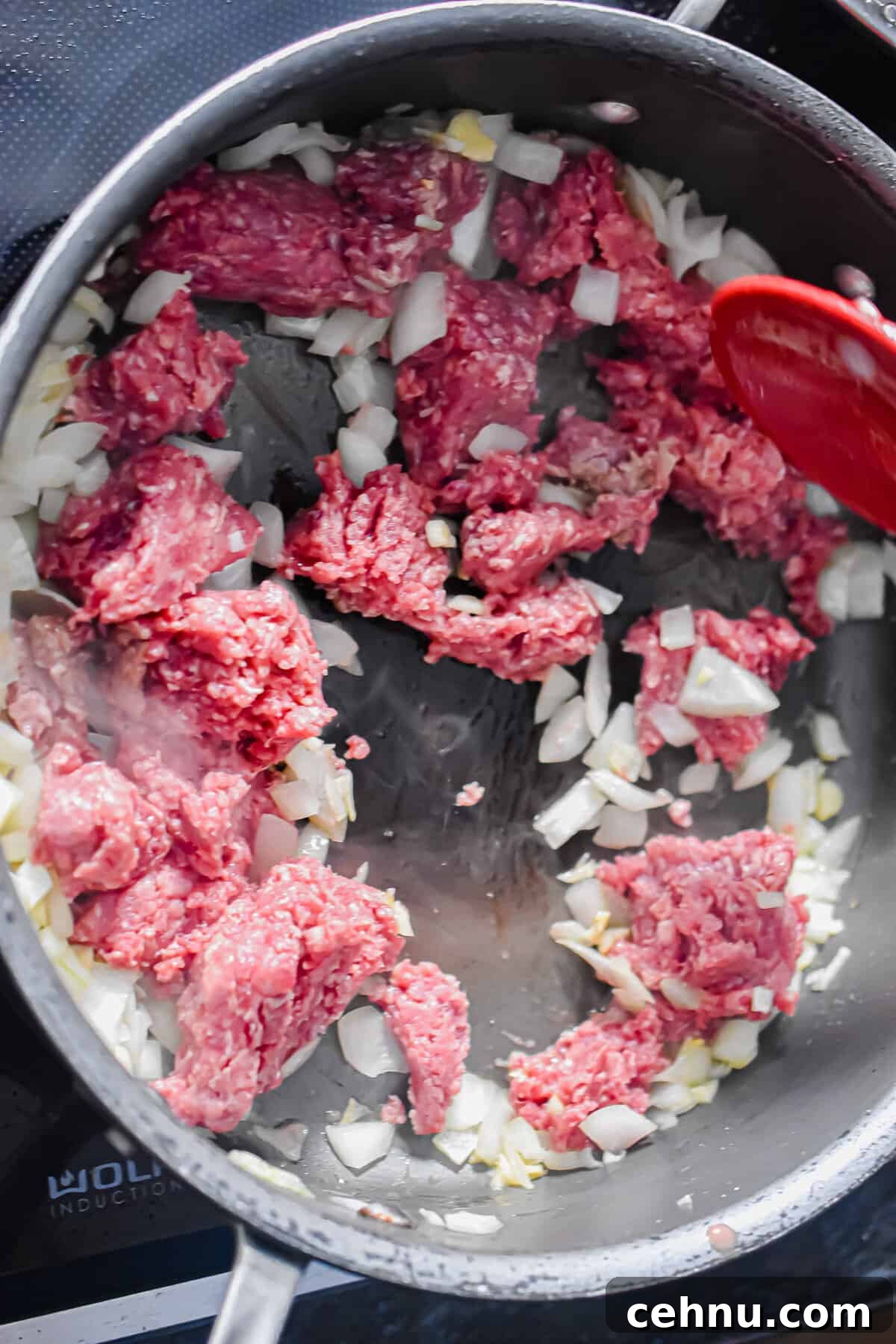 The ground beef is being cooked with the onions and garlic.
