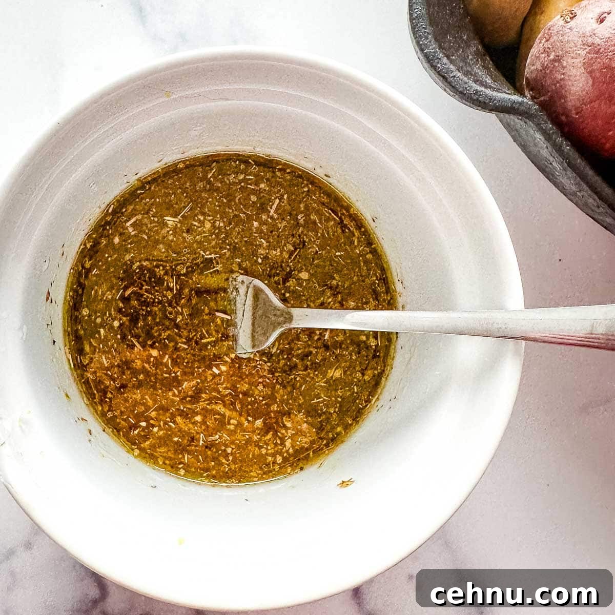 A white bowl with a mixture of lemon, olive oil, salt, pepper, and oregano.
