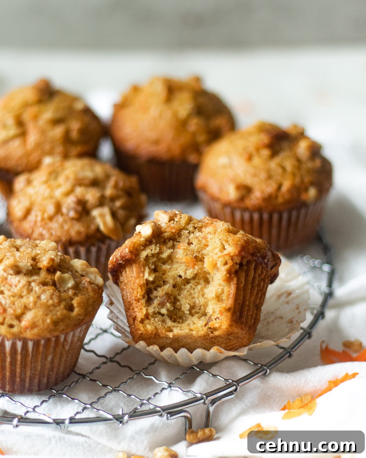 Moist Banana Carrot Muffins 4 simple banana carrot muffins on a rack, one with a bite taken out