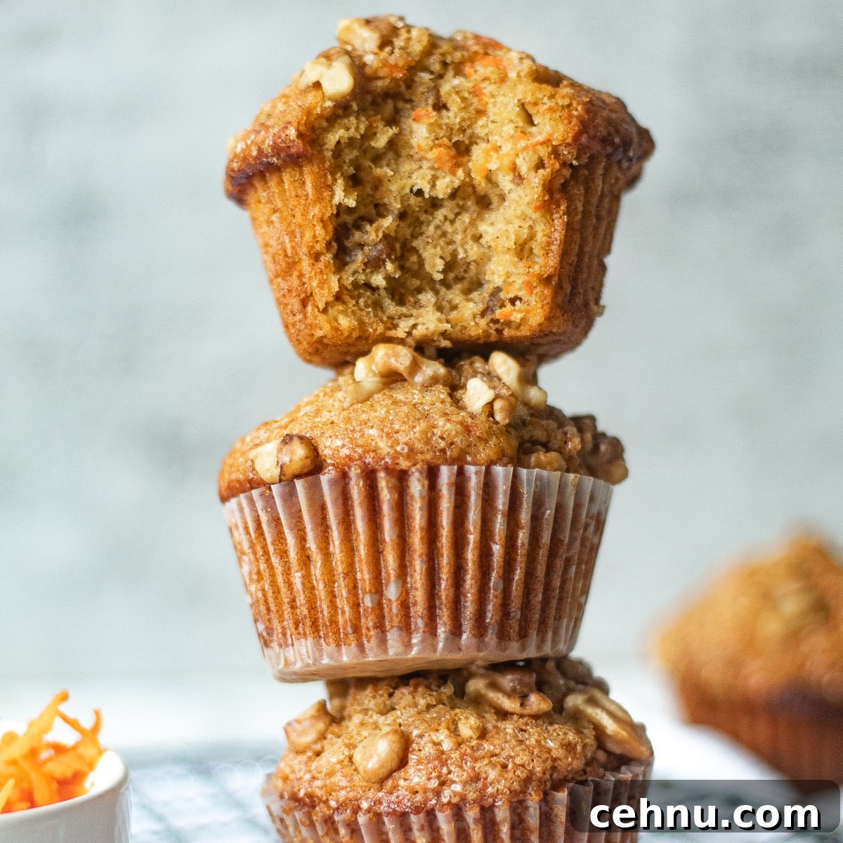 Moist Banana Carrot Muffins 9 stacked banana carrot muffins, one with a bite taken out