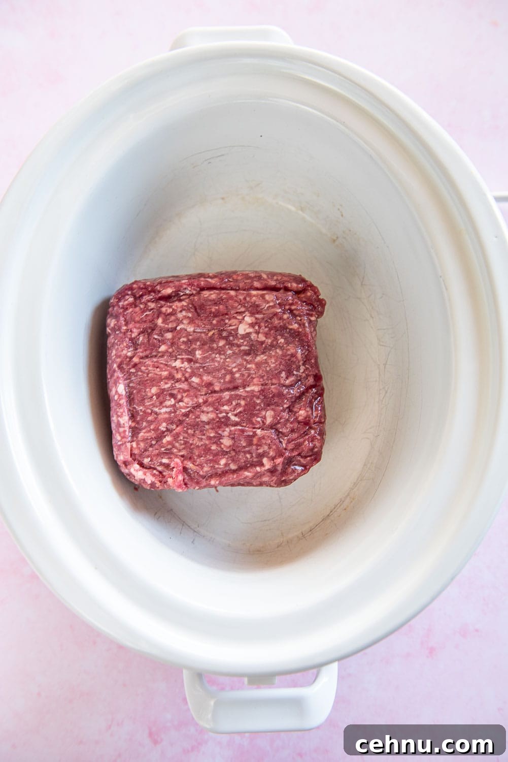 Slow Cooker Taco Meat Recipe: Tender, Flavorful Filling 4 Raw pack of ground beef inside white slow cooker bowl