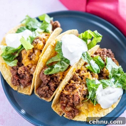 Slow Cooker Taco Meat Recipe: Tender, Flavorful Filling 7 3 beef tacos garnished with cheese, parsley, and sour cream served on a blue plate