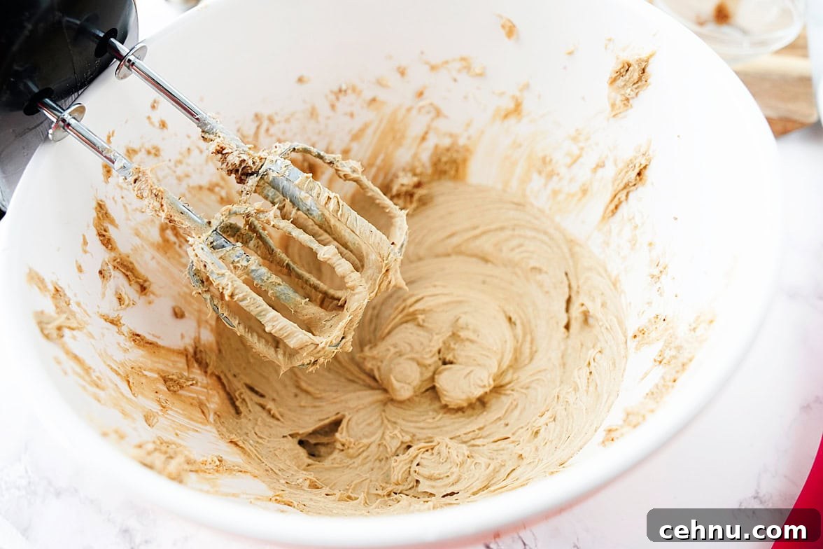 cream cheese, brown sugar, sugar, vanilla and salt being creamed together in white bowl with hand mixer