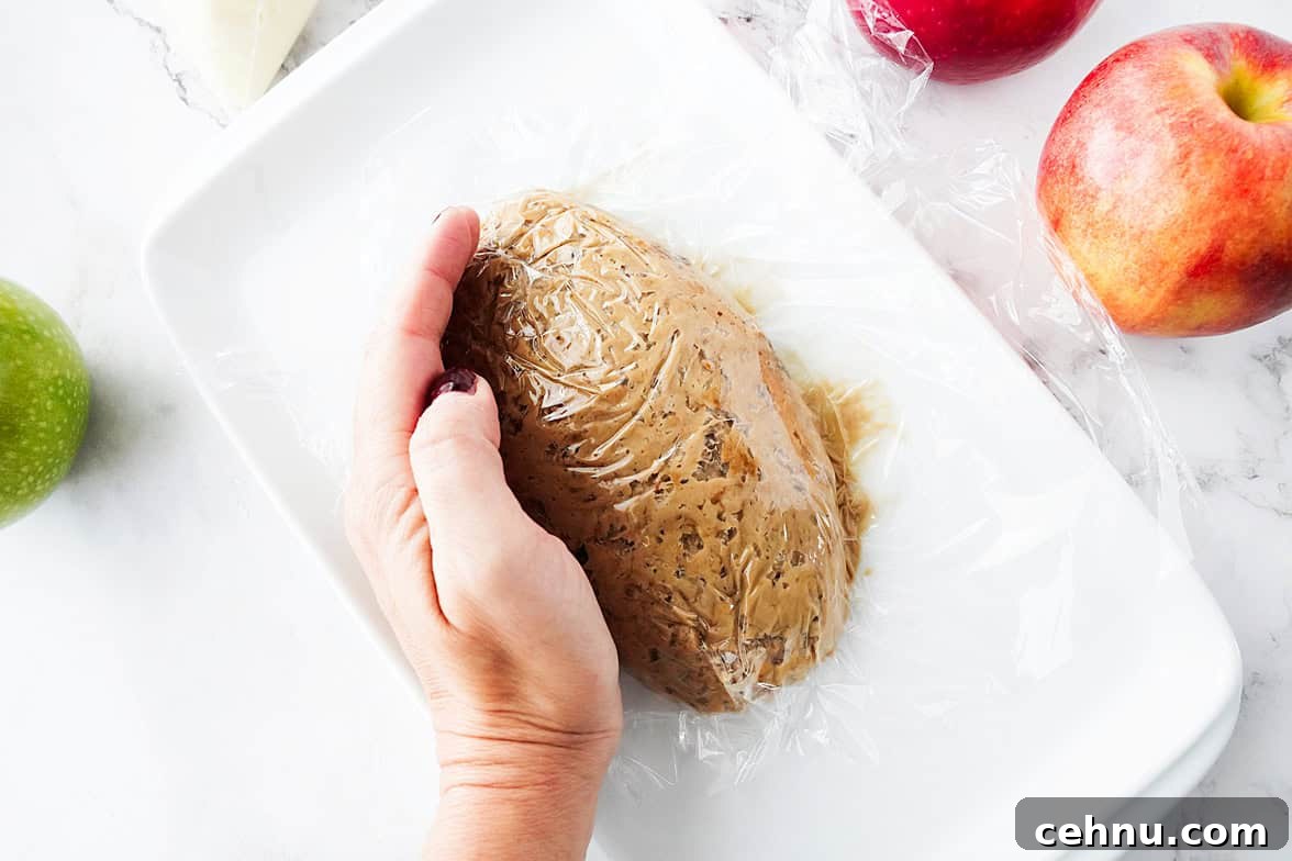 overhead shot of apple toffee dip on white plate with saran wrap over to form a football shape
