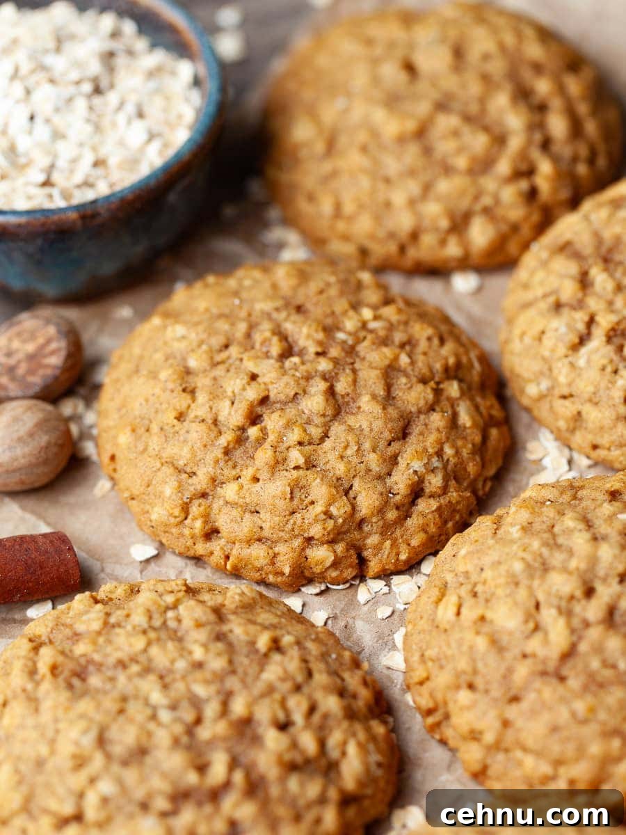 Pumpkin Oatmeal Cookies on parchment paper with a blue bowl in the back filled with oats