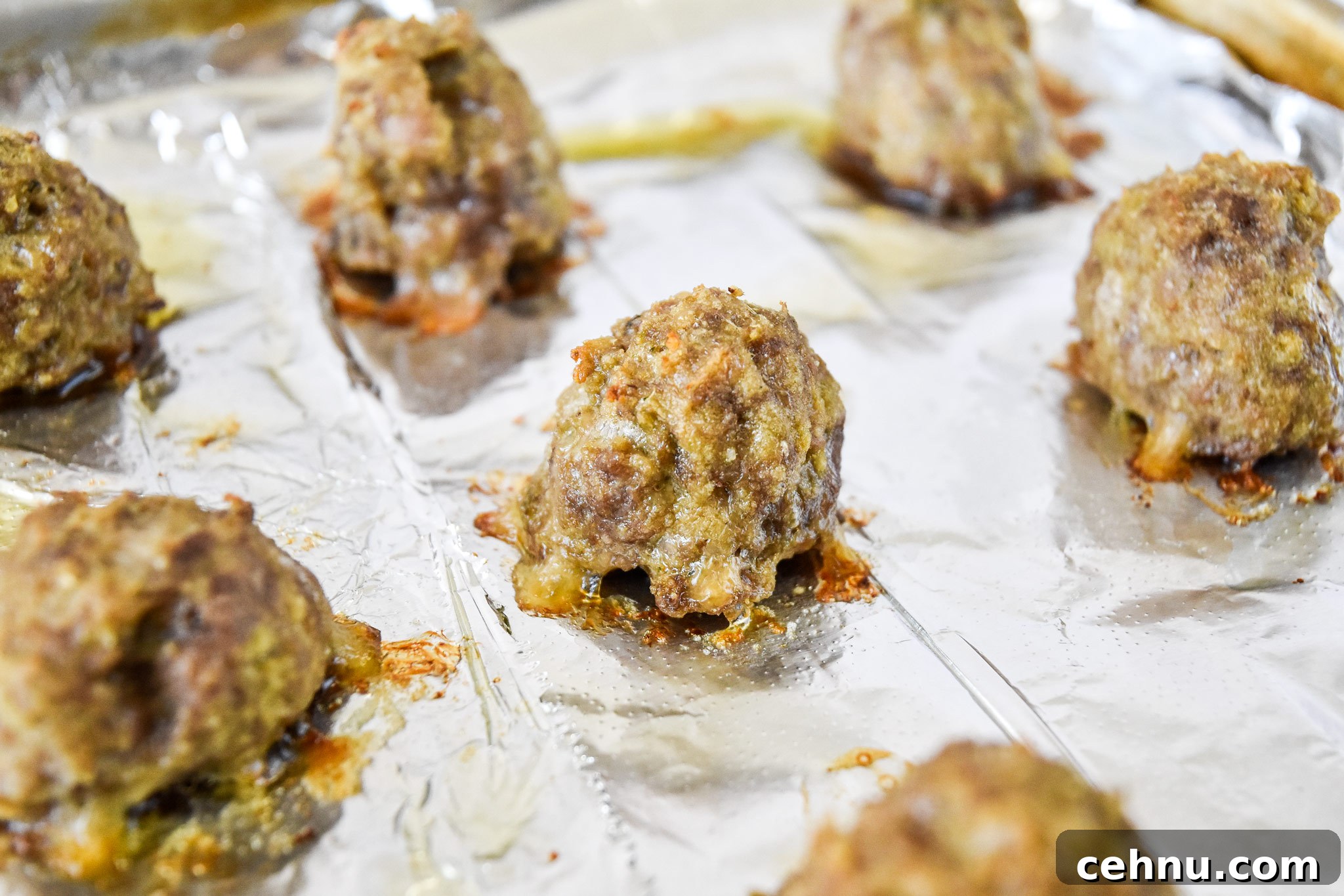 Make-Ahead Freezer Meatballs Recipe for Meal Prep 8 fresh cooked meatballs on a foil lined baking sheet.