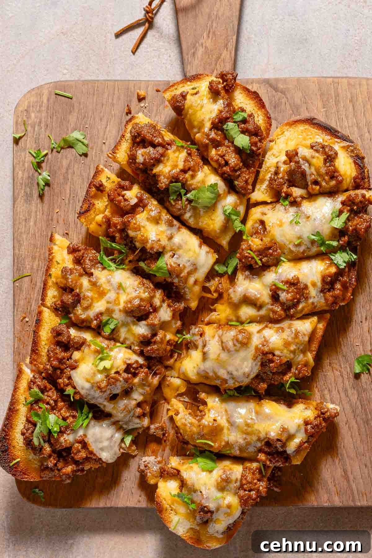 Garlic Bread Sloppy Joes Recipe for Cheesy Saucy Sandwiches 2 slices of garlic bread on cutting board topped with sloppy joe meat and melted cheese.