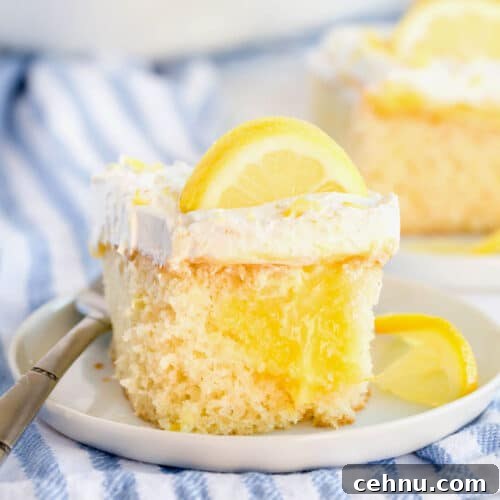 A piece of lemon poke cake garnished with lemon slices on a white plate