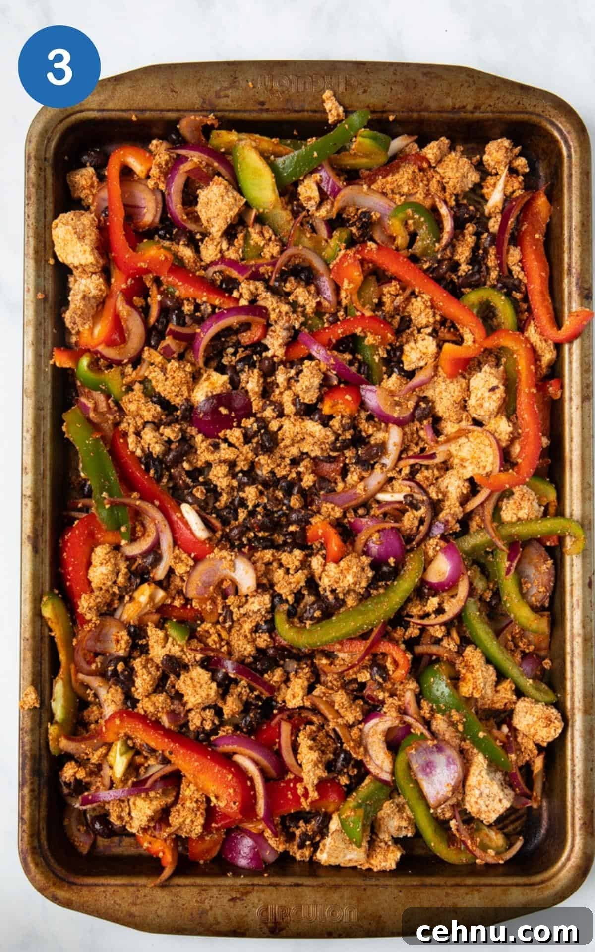 Spices, Black beans, Red Pepper, Tamari, Olive oil, red onion, and green pepper in a baking pan for homemade tofu fajitas.