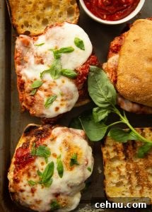 overhead shot of open sandwiches on baking tray with basil and pot of marinara sauce