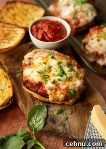 parmesan chicken sandwich on chopping board surrounded by basil, parmesan and ciabatta