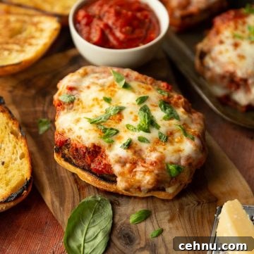 parmesan chicken sandwich on chopping board surrounded by basil, parmesan and ciabatta