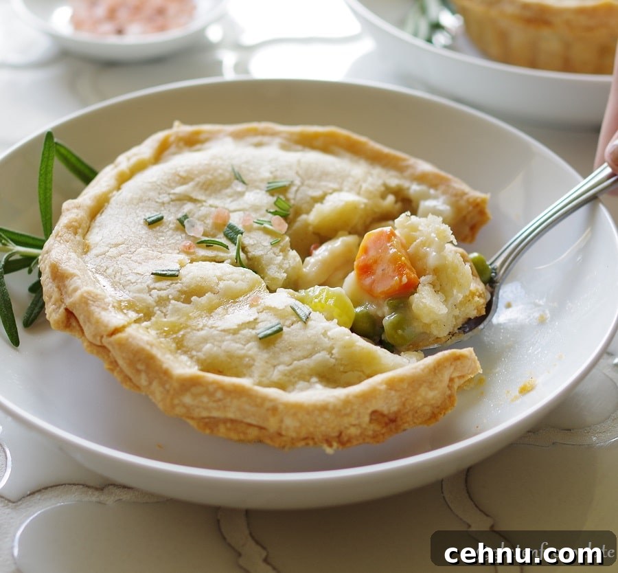 Gluten Free Chicken Pot Pie Recipe with Flaky Crust 4 a Gluten-Free Chicken Pot Pie topped with salt and rosemary on a white plate, with a spoon taking a bite out