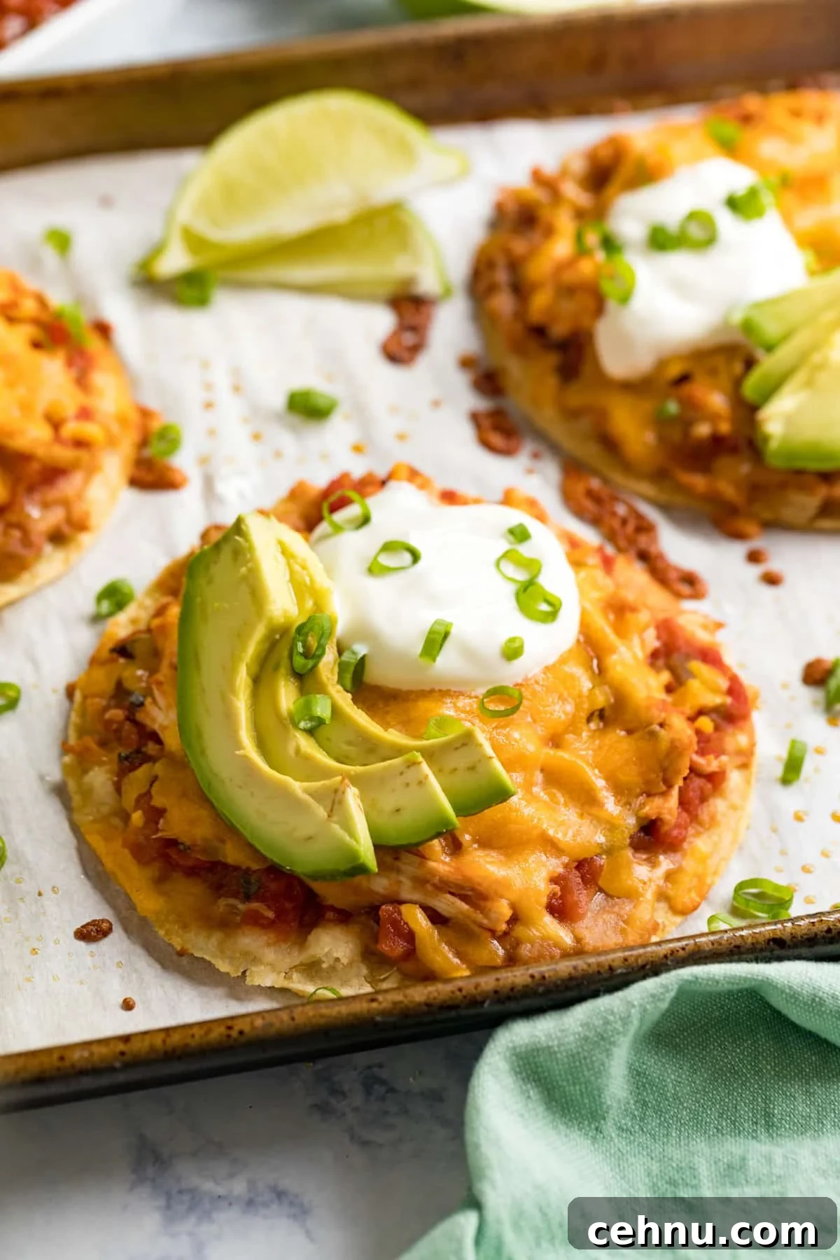 A side angle image of a dressed chicken tostada on a pan with more behind it.