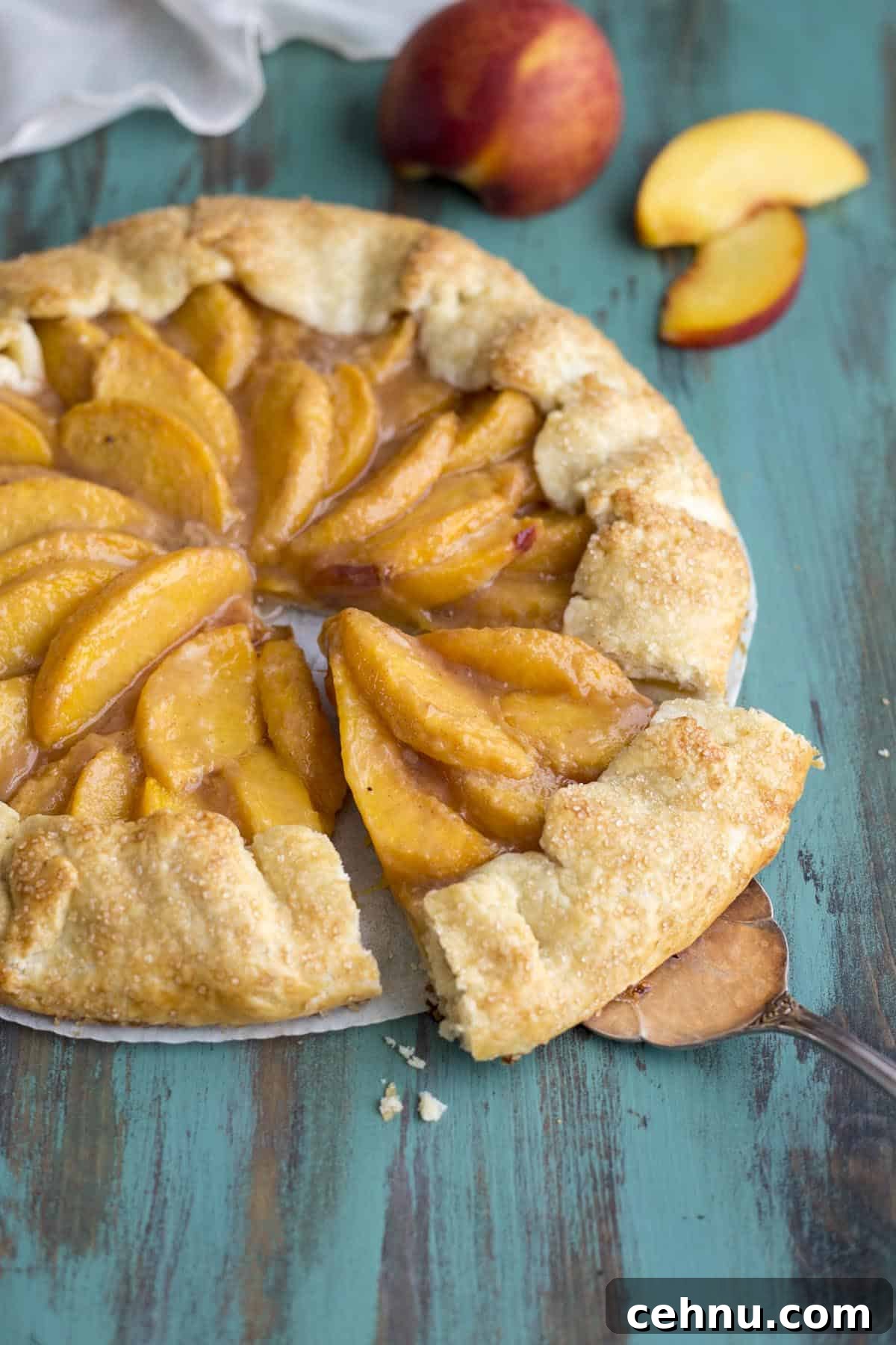 Rustic Peach Crostata or Galette Recipe 9 A slice of peach galette is taken from the full pie with a pie server.
