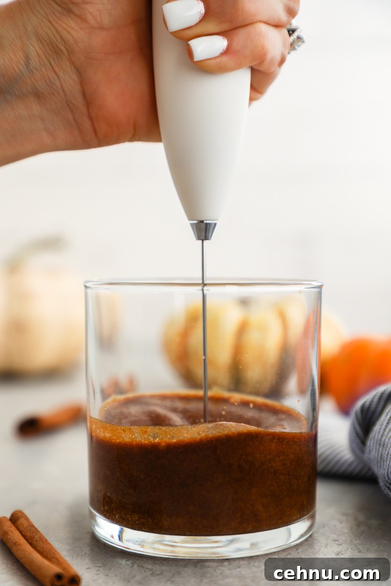 Espresso, pumpkin puree, maple syrup, pumpkin pie spice and vanilla are blended together in a clear glass with a milk frothing wand