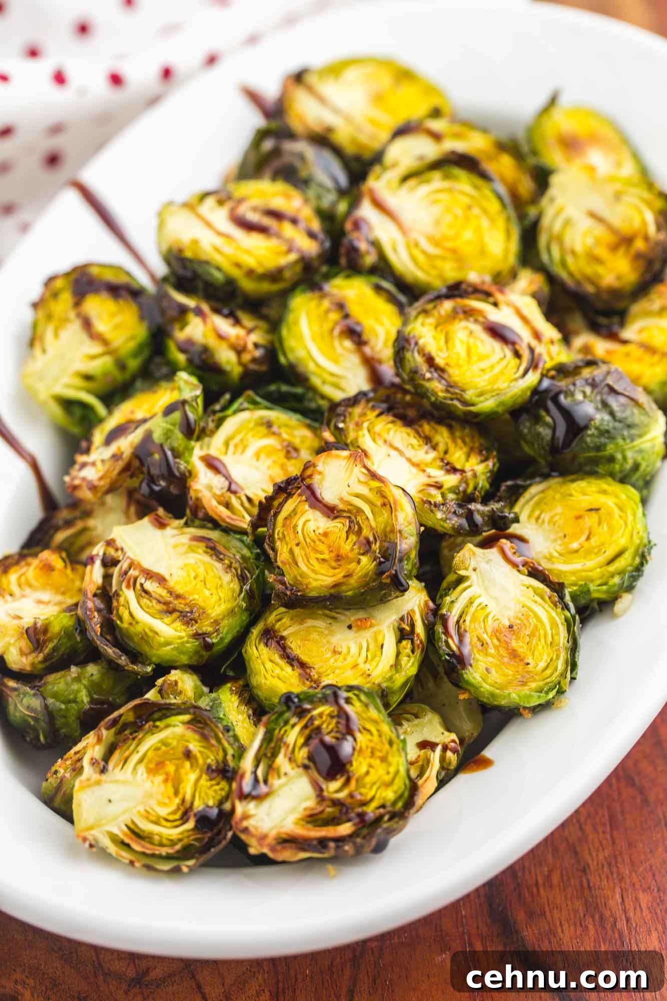 A white oval plate with roasted brussels sprouts and balsamic glaze