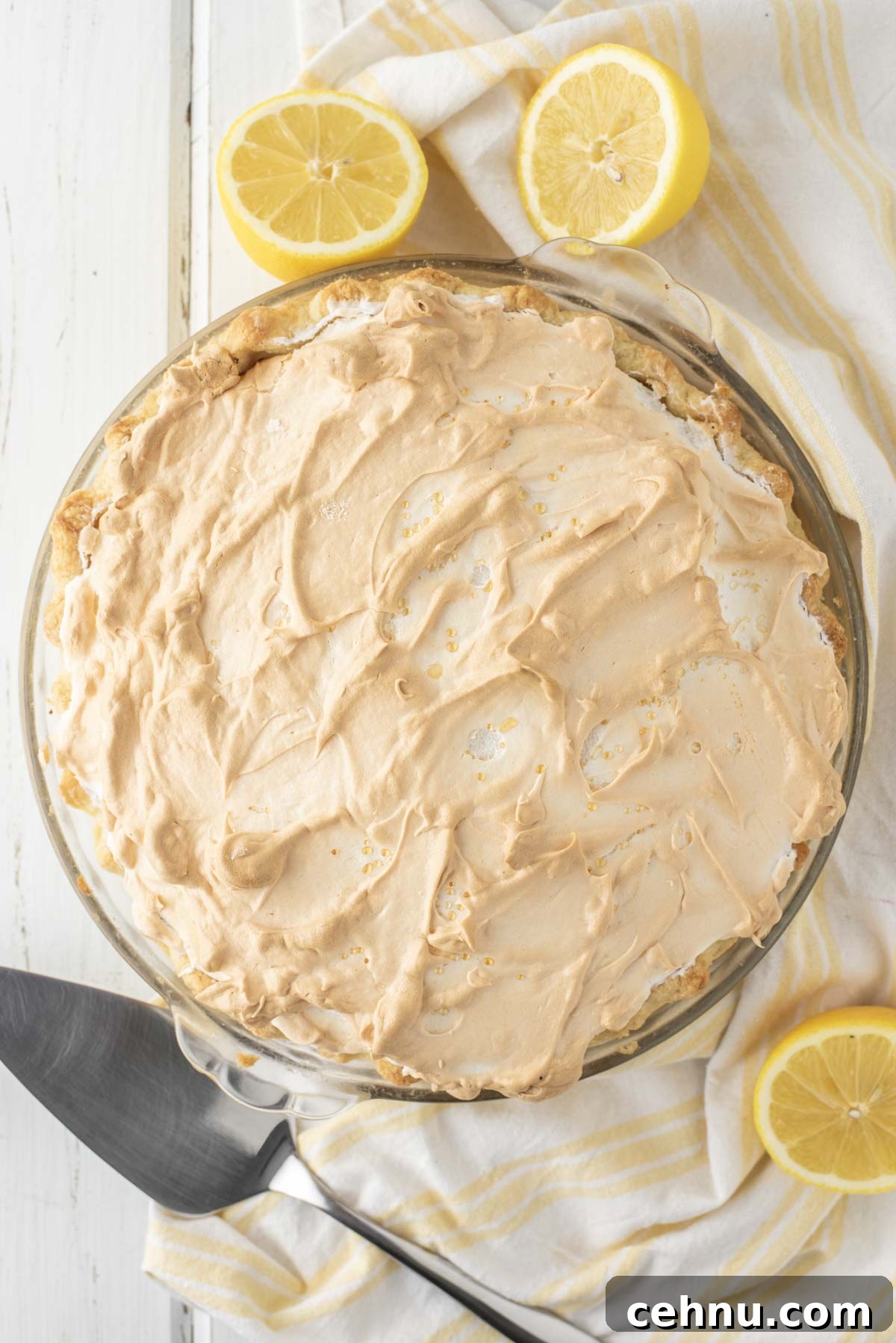 overhead shot of lemon meringue pie in glass pie dish on white background