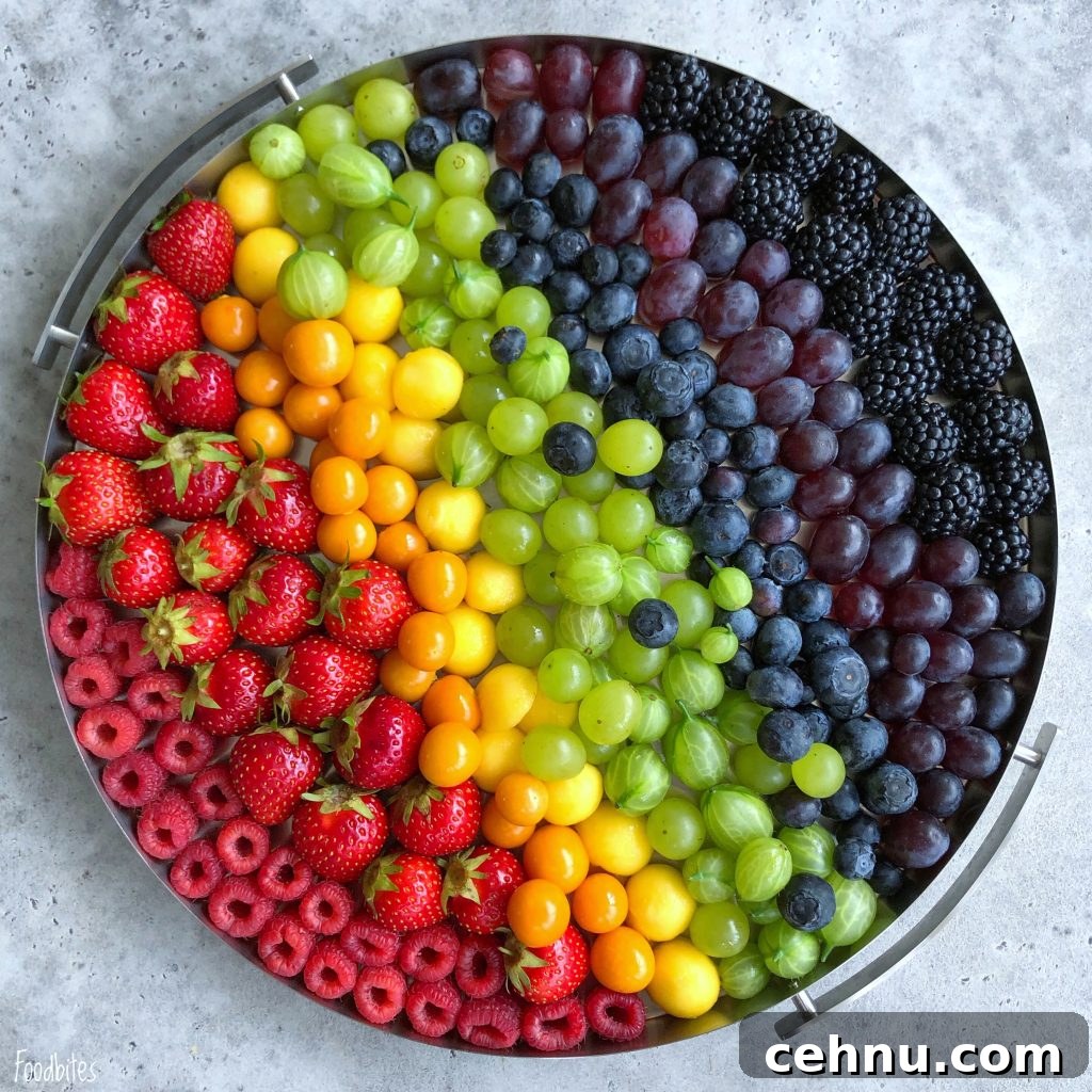 A round tray displays an array of fresh fruits arranged in rainbow-like rows—these colorful bites make for both a beautiful presentation and a health-conscious addition to your favorite food recipes.