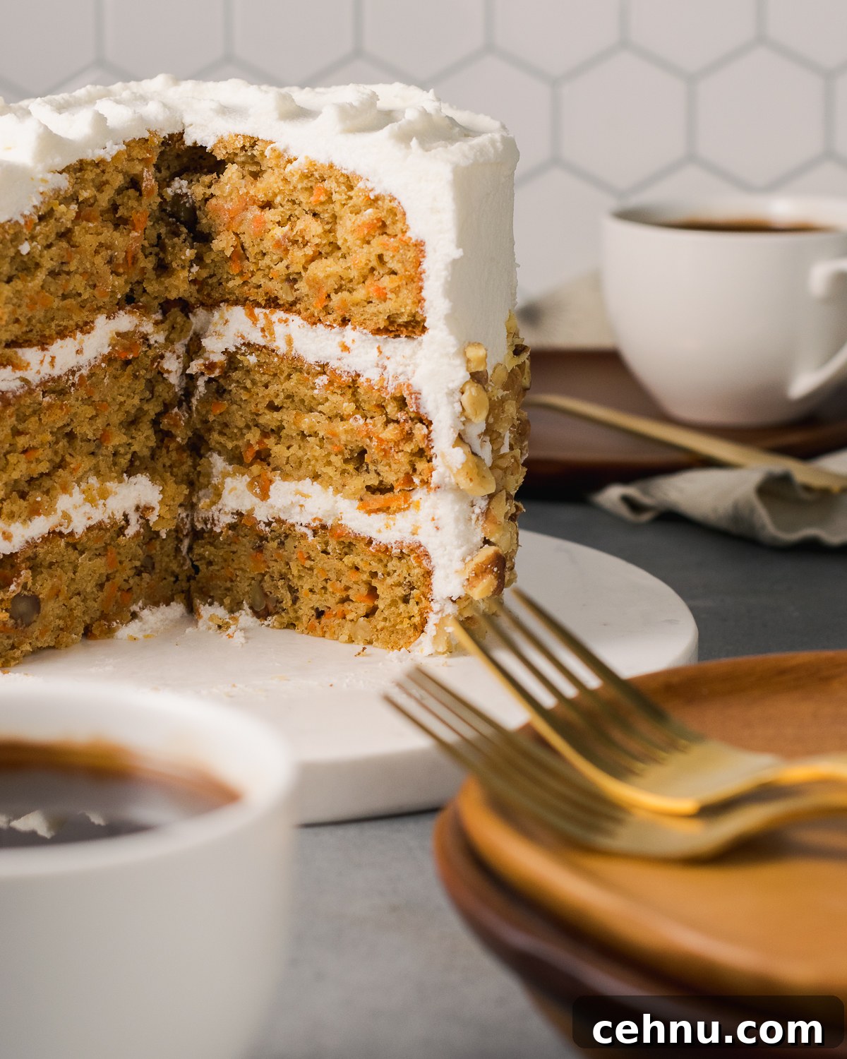 A sliced carrot cake on a table with cups of coffee and plates.