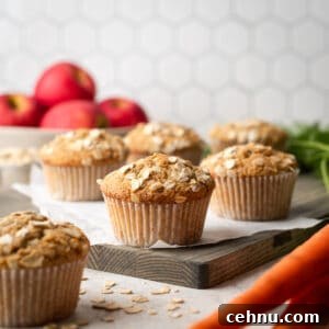 Applesauce carrot muffins sitting on a wooden cutting board.
