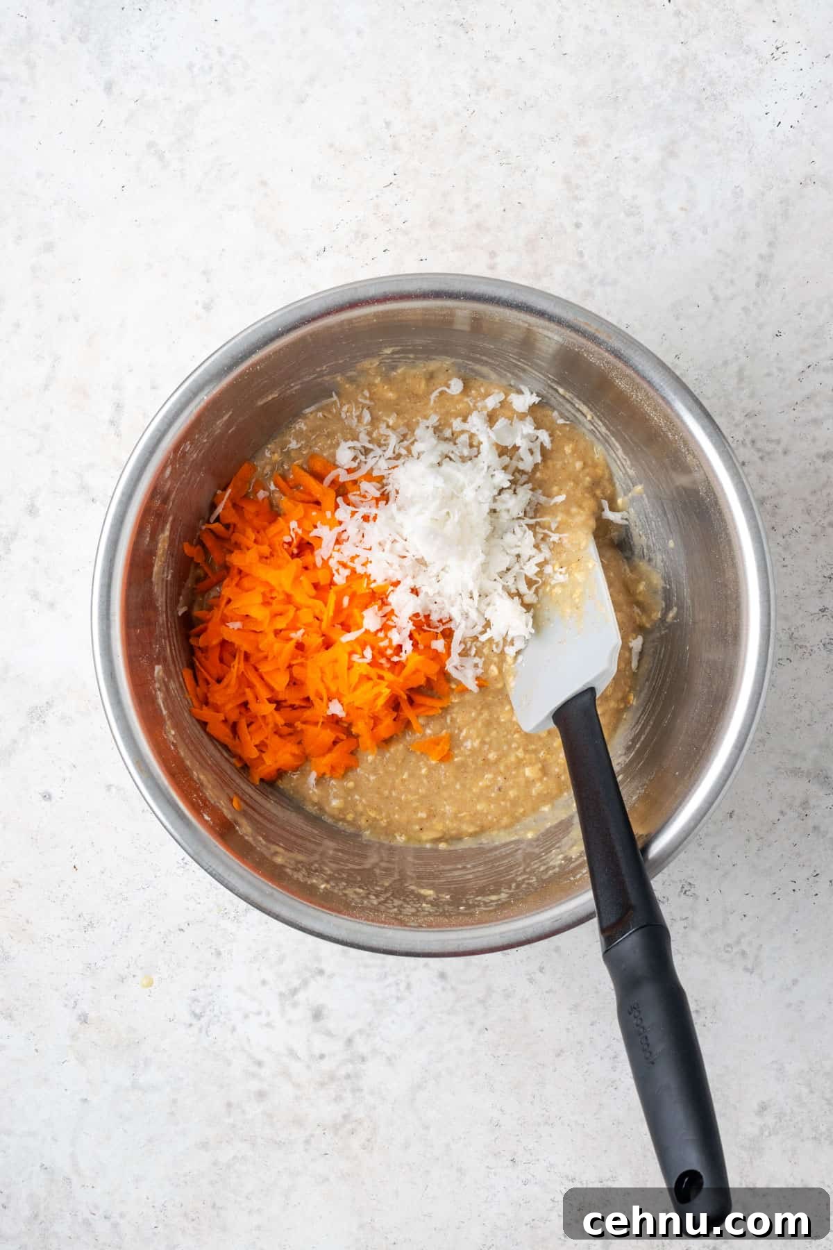 Moist Applesauce Carrot Muffin Recipe with Cinnamon 8 Shredded carrots and shredded coconut being added to the mixed muffin batter.
