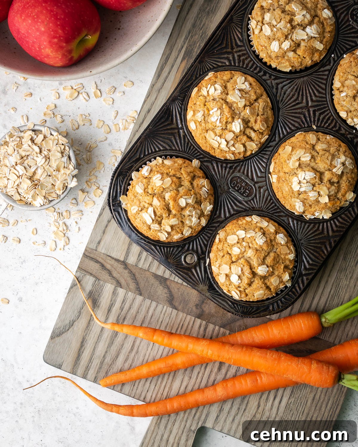 gf apple carrot muffins Applesauce carrot muffins sitting on a table with carrots and apples.
