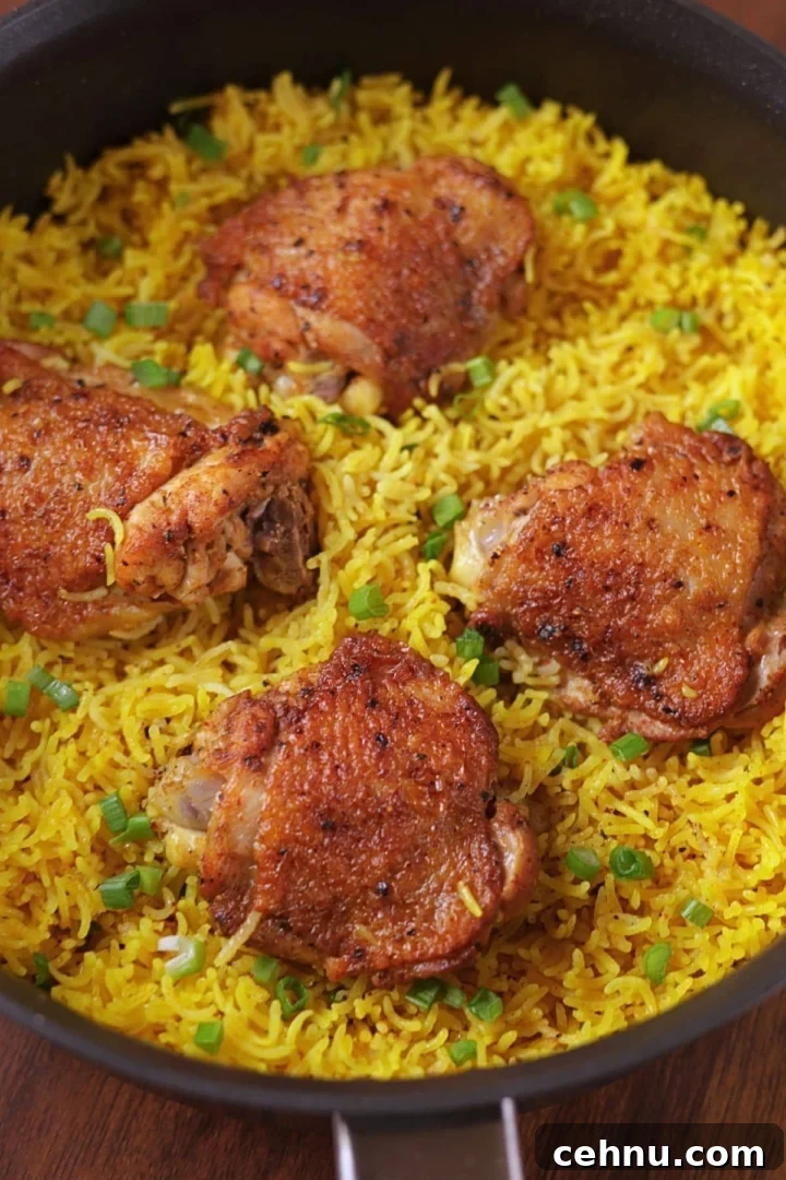 Easy one pan chicken and yellow rice with four chicken thighs in a skillet.